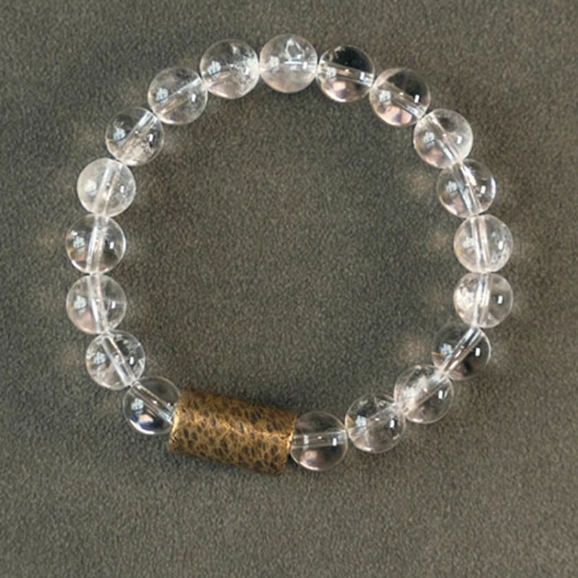 Natural quartz crystal bracelet with purple phantom and rutilated stones on neutral grey fabric background