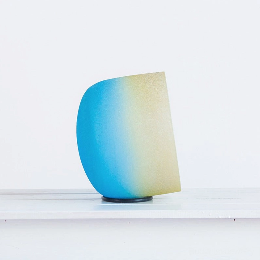 Low angle view of white crystal singing bowl on rubber base showing three-dimensional craftsmanship