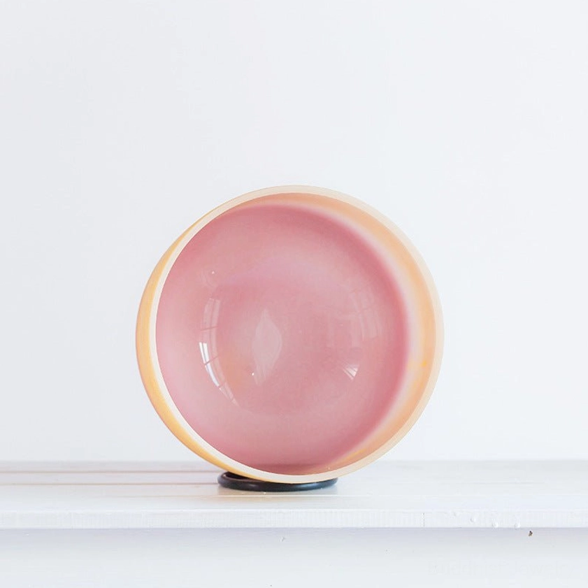 Top-down overhead view of crystal singing bowl with pink inner bowl and yellow-pink ombre design, displaying black anti-slip rubber base for stability