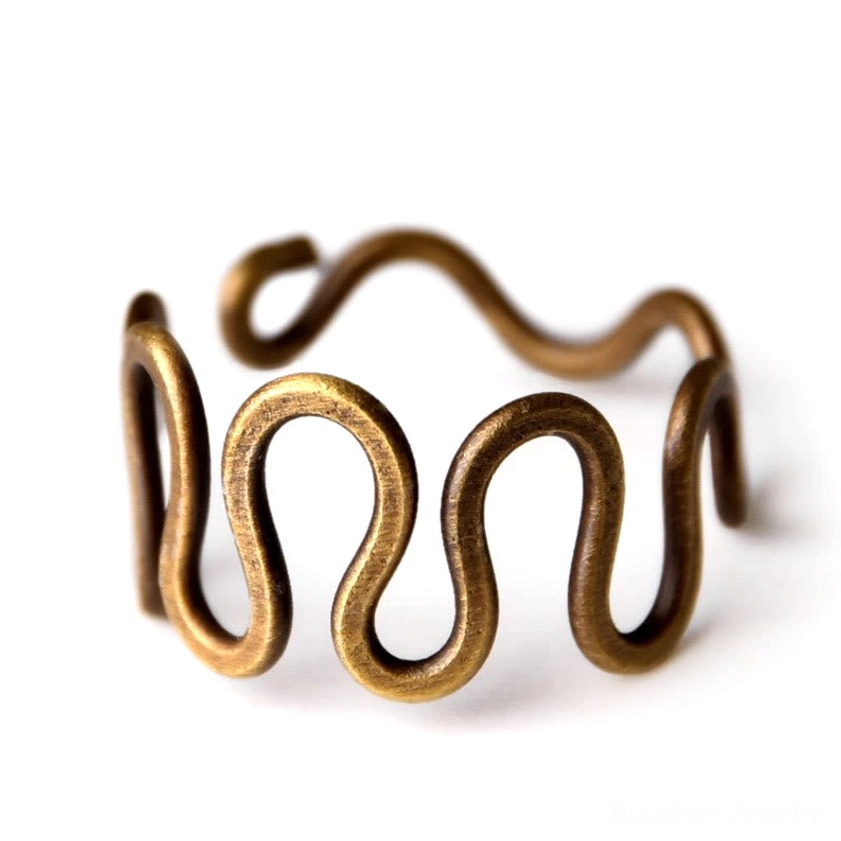 Curved brass wave ring overhead close-up on white background showing thick antique brass wire and adjustable ends