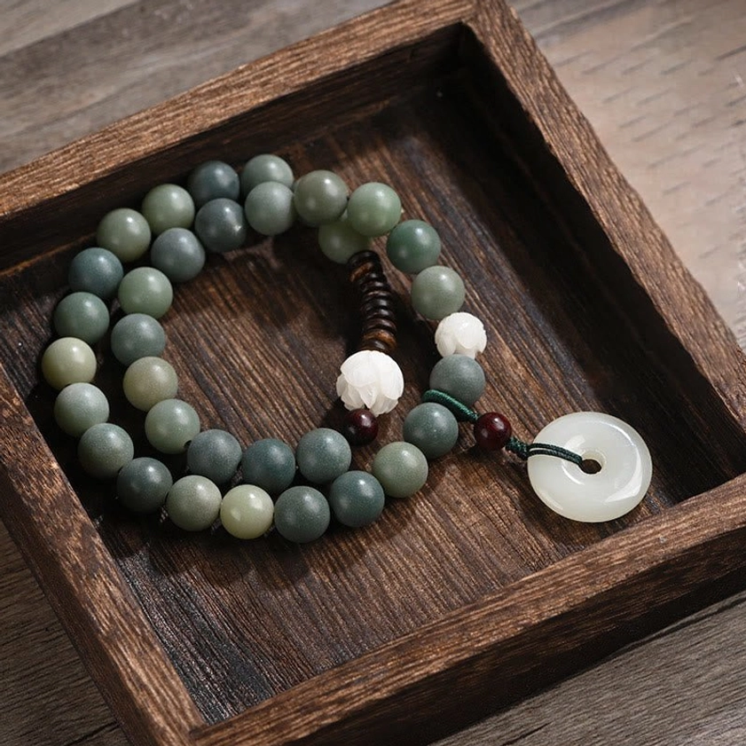 Cyan bodhi seed double wrap bracelet with jade peace buckle pendant displayed flat lay on wooden tray, showing gradient green beads and white lotus accent