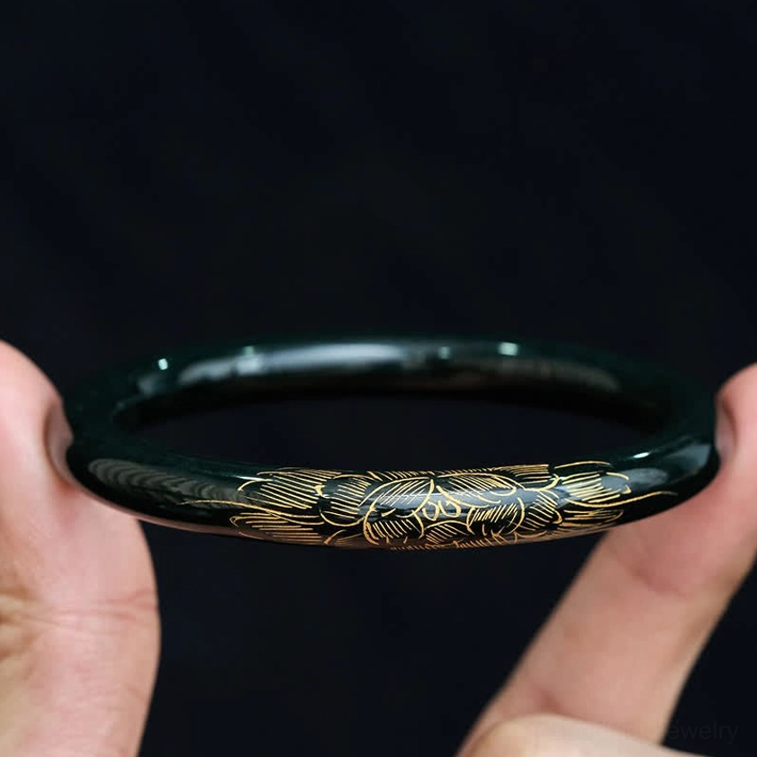 Cyan jade bangle bracelet hand held showing gold engraved patterns and polish finish