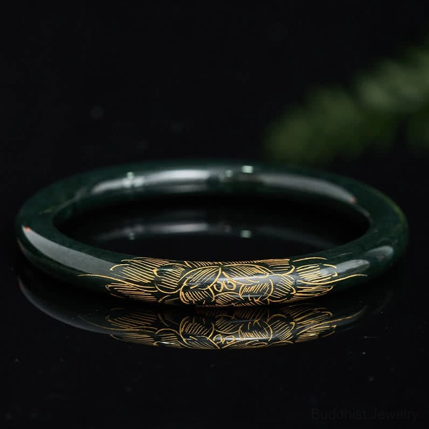 Natural cyan jade bangle bracelet with gold engraved lotus and koi fish symbols, top down flat lay view