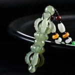Cyan Hetian jade Dorje Vajra pendant necklace with hollow carved five-pronged design on black ceramic background, showing translucent jade texture