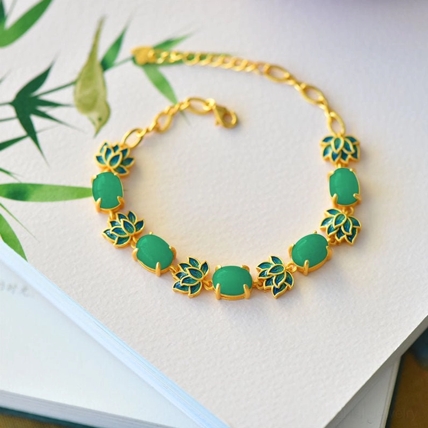 Green cyan jade and lotus bracelet with gold metal chain and blue enamel lotus charms overhead flat lay