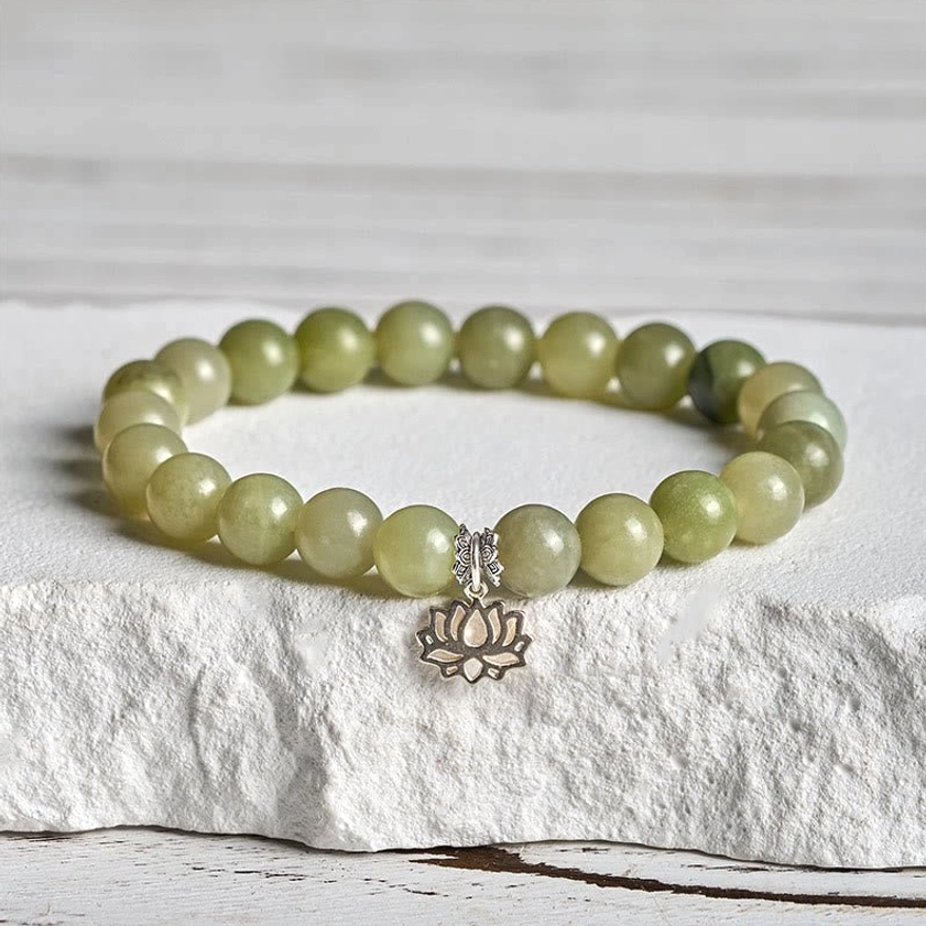 Cyan jade lotus bracelet with 925 sterling silver charm displayed on white stone, showing gradient green beads and hollow lotus pendant