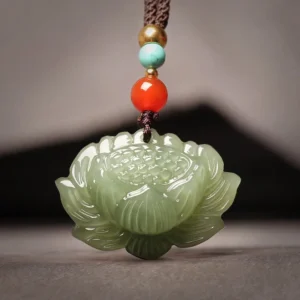 Hetian cyan jade lotus flower pendant necklace with multi-color beaded rope, flat lay front view on dark background showing carved 3D lotus design