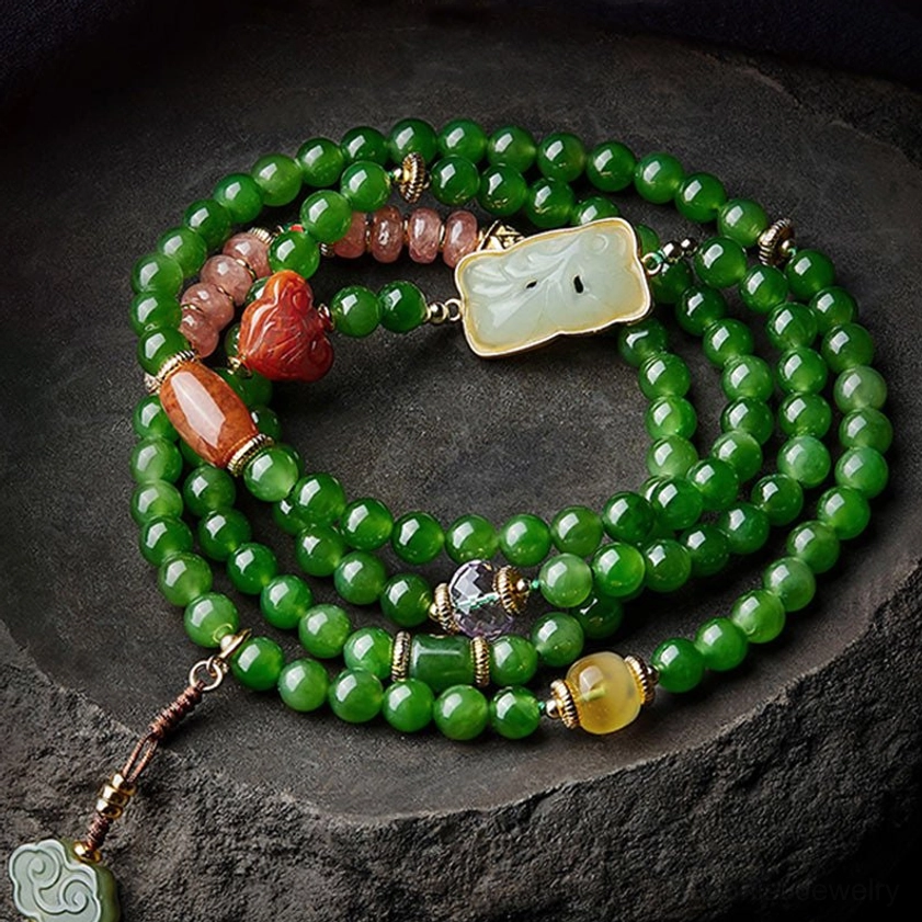 Close-up overhead view of jade and agate mala beads with carved Buddha head and white Hetian jade pendant