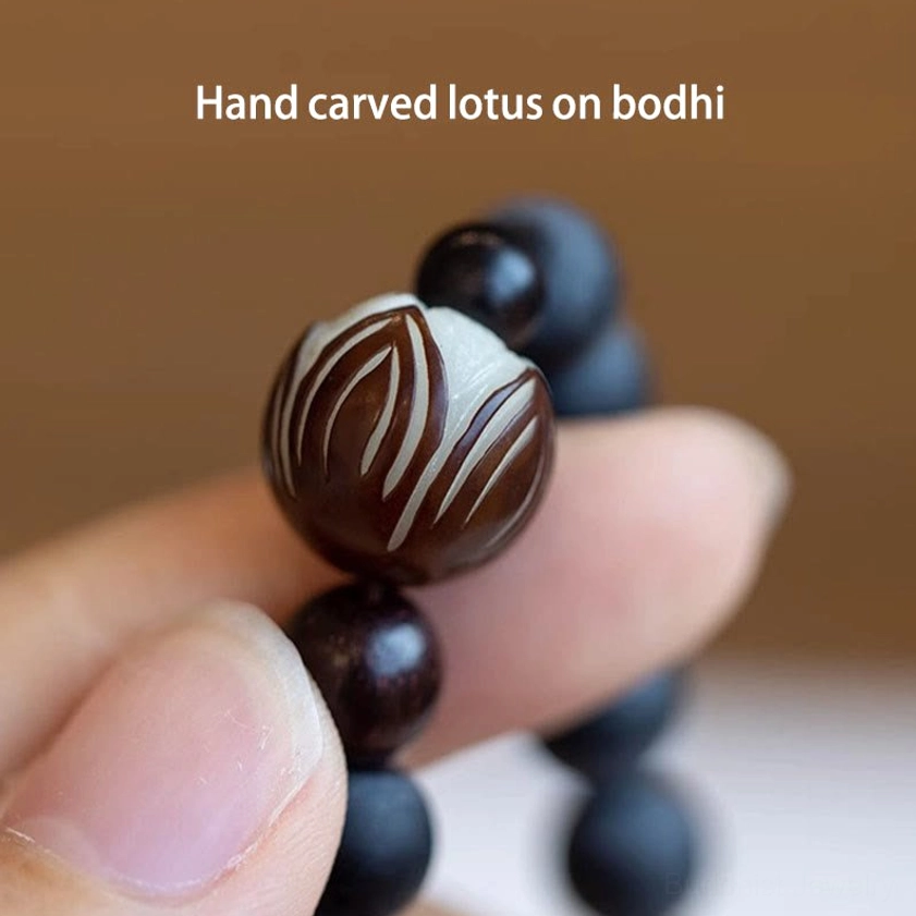 Close-up detail shot of hand-carved brown lotus bodhi bead with matte black cypress beads on prayer bracelet