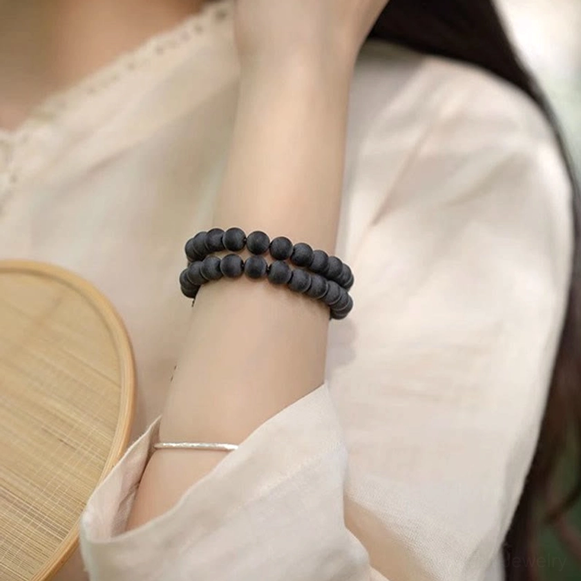 Single-wrap cypress bodhi meditation bracelet worn on female wrist with linen clothing in natural lifestyle setting