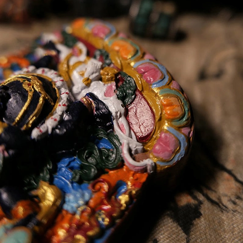 Right angled overhead view of hand-painted Daikokuten Buddha statue featuring lotus-shaped rim, black body with gold accents and polychrome details