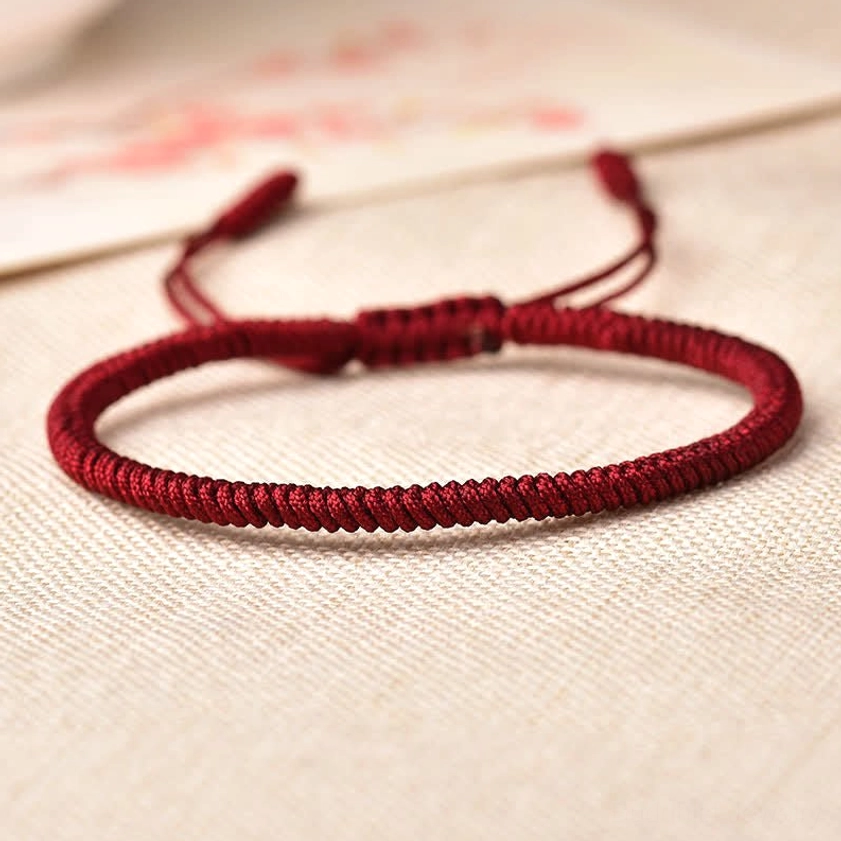 Dark red handcrafted Buddhist protection bracelet with plain braided weave and adjustable drawstring tail