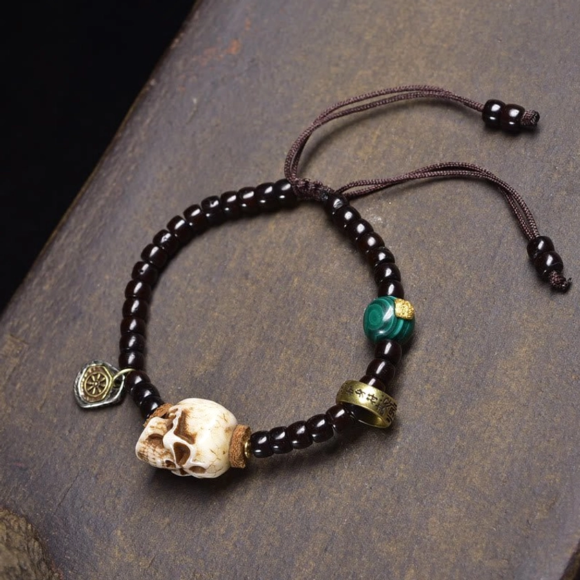 Dark black beaded bracelet with green stone and bronze metal charm detail