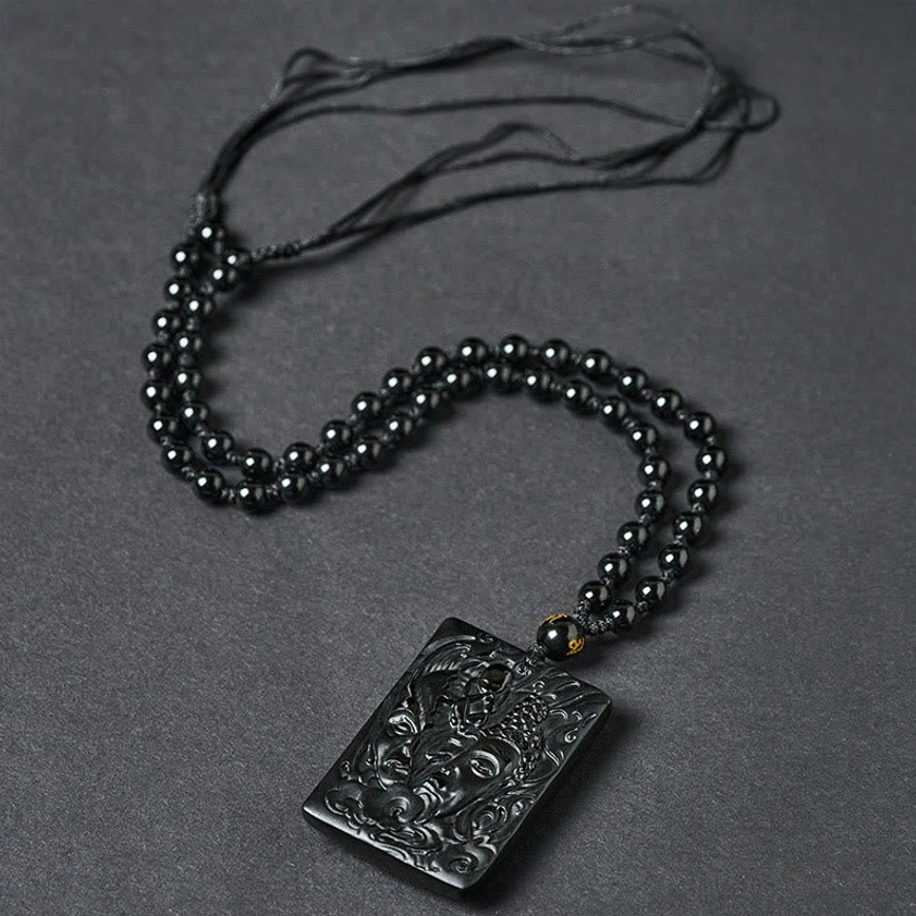 Complete black obsidian demon buddha necklace flat lay with full cord and decorative stone bead