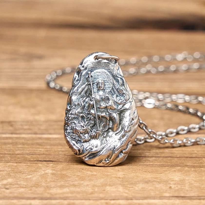 Dizang Bodhisattva copper pendant with detailed silver relief carving, flat lay on wooden surface