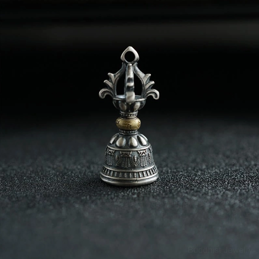 Front upright view of Buddhist dorje bell pendant with five-pronged vajra top and carved sacred motifs in sterling silver