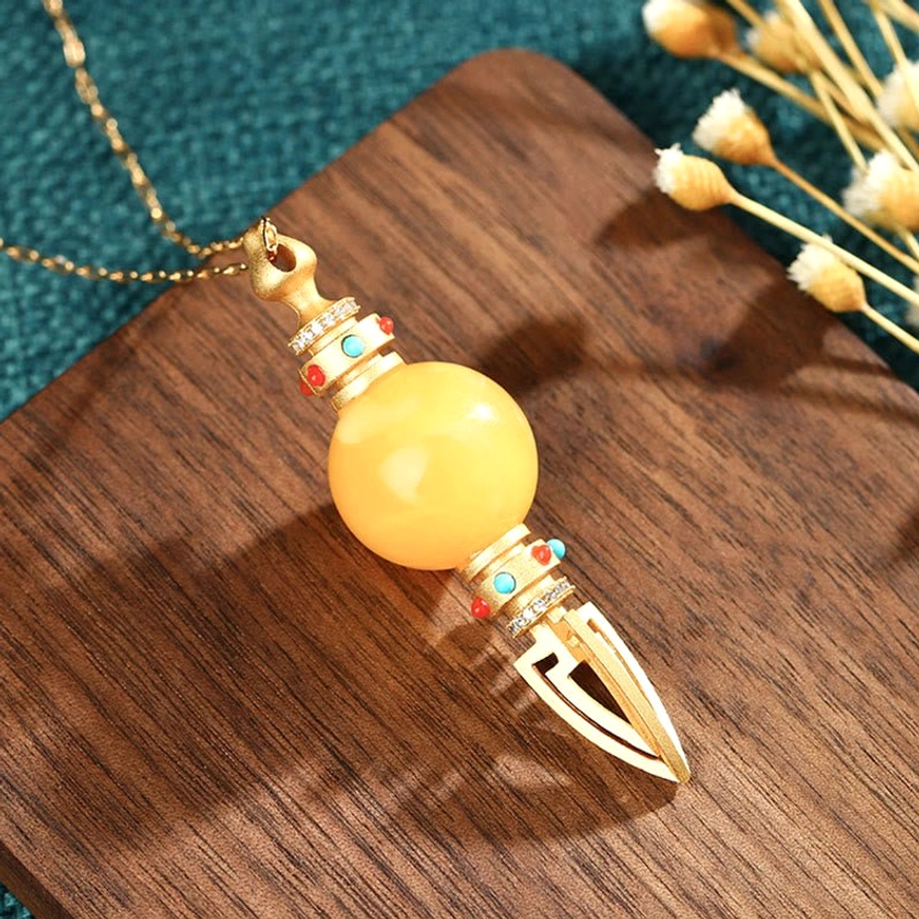 Buddhist vajra necklace with fine gold chain, side view showing amber stone detail and gemstone accents