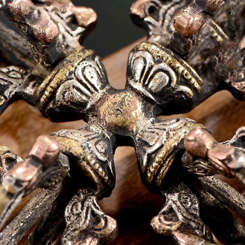 Detailed overhead closeup of double dorje vajra center with lotus petal carvings and copper-toned prongs - Buddhist ritual details