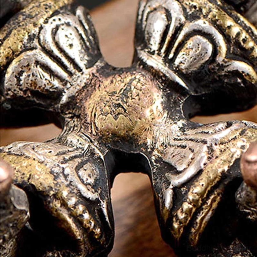 Extreme closeup of double dorje vajra center section with detailed relief carvings and aged metal patina - Buddhist ritual craftsmanship