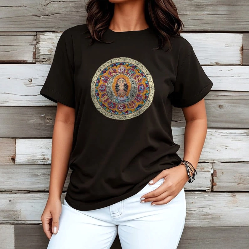 Female model wearing black Dorje Vajra Mandala Buddhist t-shirt with detailed mandala chest print, styled with white jeans on wooden background