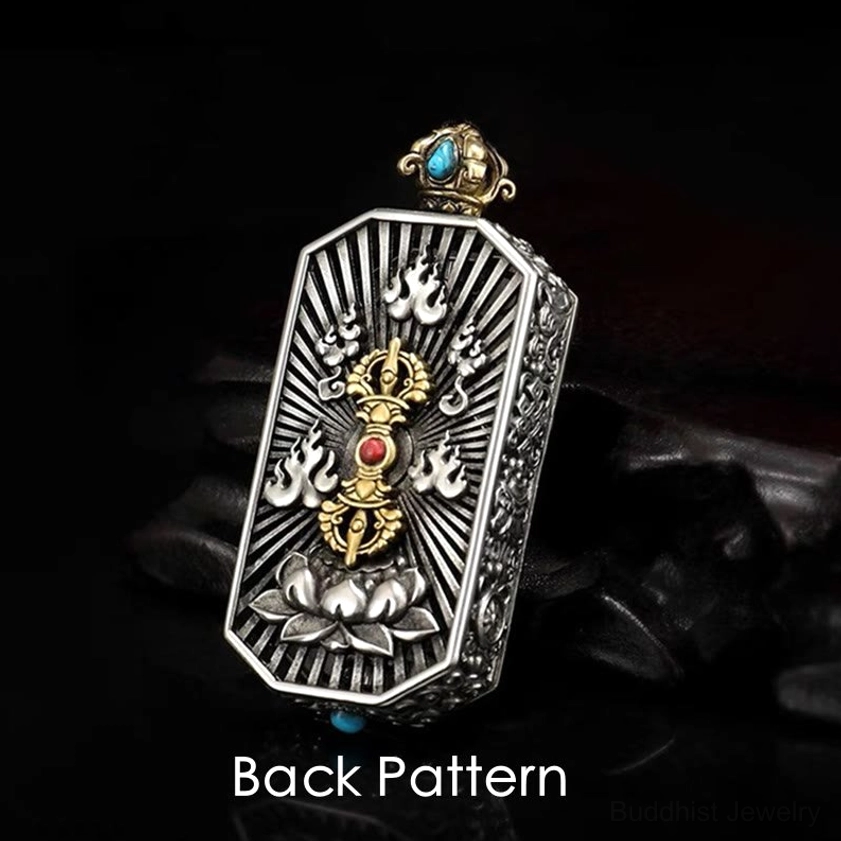 Back side of Buddhist dorje vajra pendant showing engraved lotus base with radiating filigree and blue red gemstone inlays