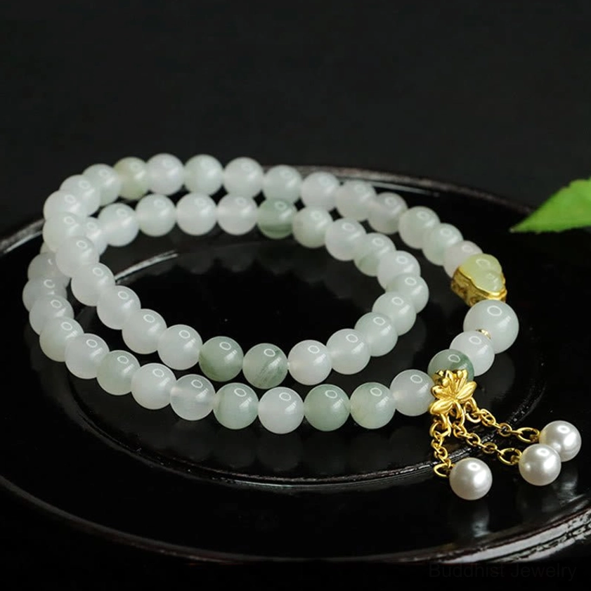 Double circle Tianshan jade bracelet with three dangling white pearl charms and gold bead accent on black ceramic tray
