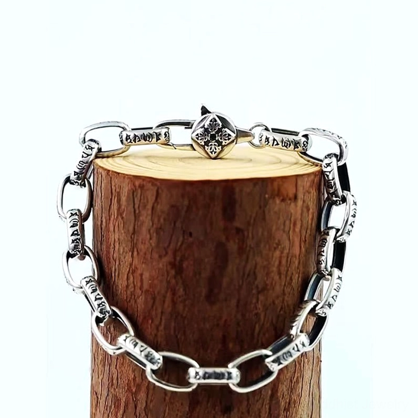 Central Double Dorje charm on copper Buddhist bracelet with engraved mantra script links, displayed on wooden stand