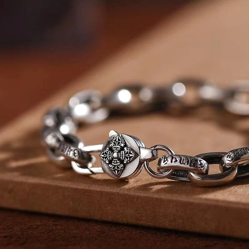 Double Dorje Buddhist bracelet close-up showing intricate engraved script links and decorative clasp detail