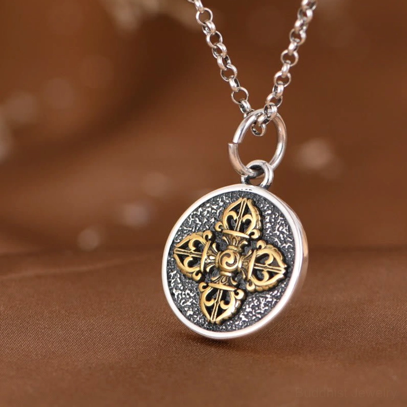 Detailed view of double dorje vajra gold embossed design on silver pendant