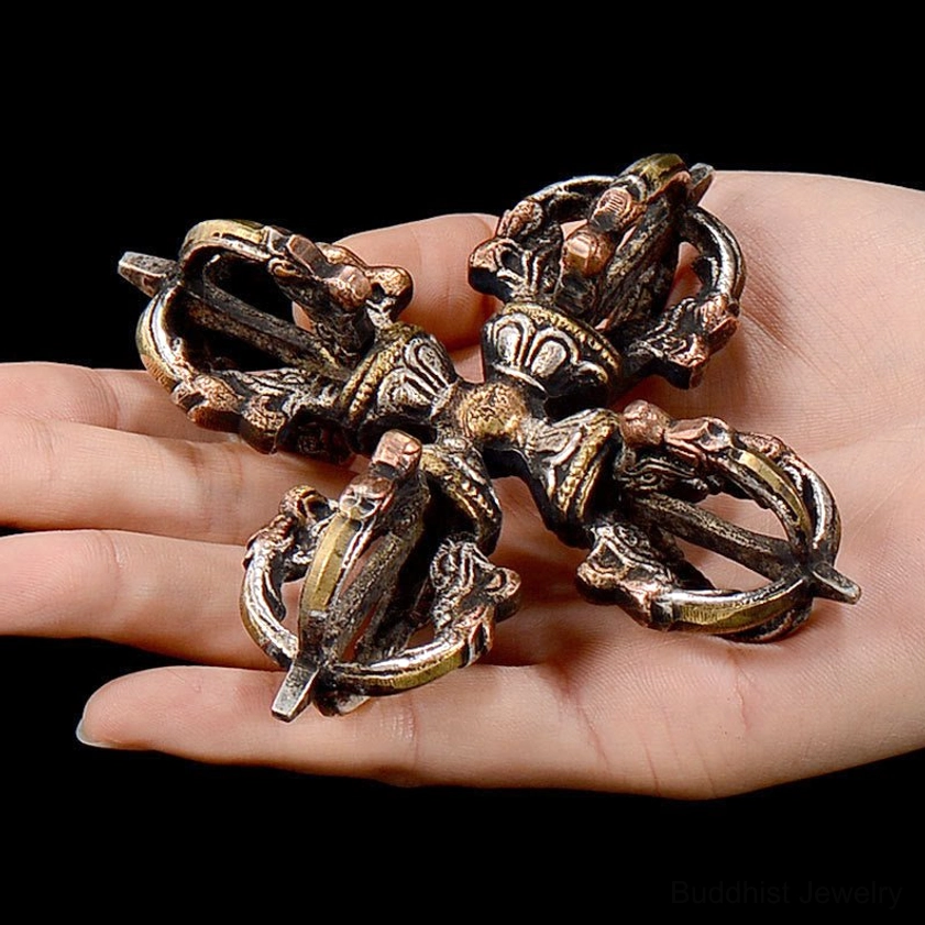 Double dorje vajra held in hand showing size - handheld Buddhist thunderbolt ritual tool with aged silver-bronze finish