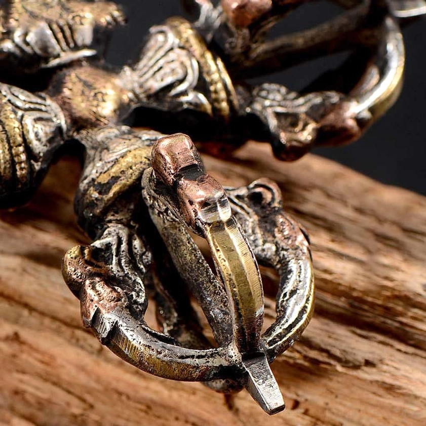 Close-up side view of double dorje vajra showing polished bronze accents and pronged ritual ends - Buddhist dorje detail