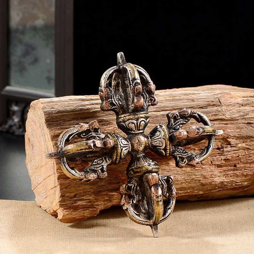 Three-quarter front view of handcrafted double dorje vajra on wooden surface - Buddhist symbol for inner strength and enlightenment