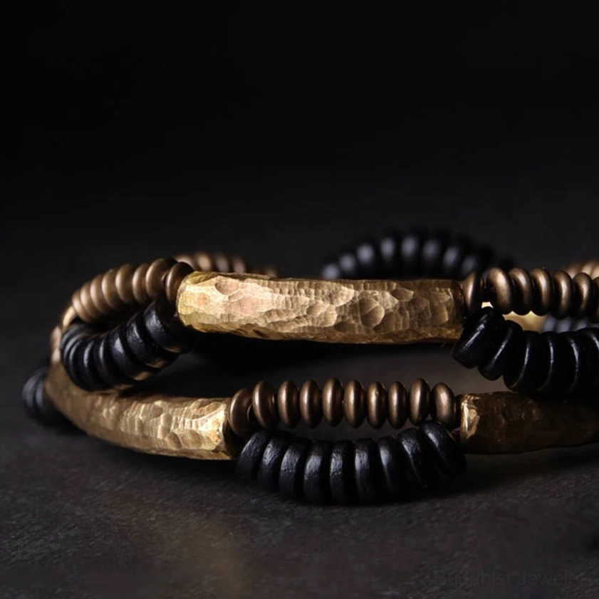 Stacked layered ebony wood and copper Buddhist bracelets showing vintage design with hammered copper accents from top-down view