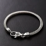 Double Vajra Buddhist bracelet with swastika symbol and lobster clasp, handmade copper chain displayed on dark leather background