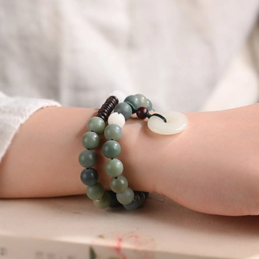 Double wrap bodhi seed bracelet on forearm showing gradient cyan beads, white peace buckle charm, and red sandalwood spacer beads side view