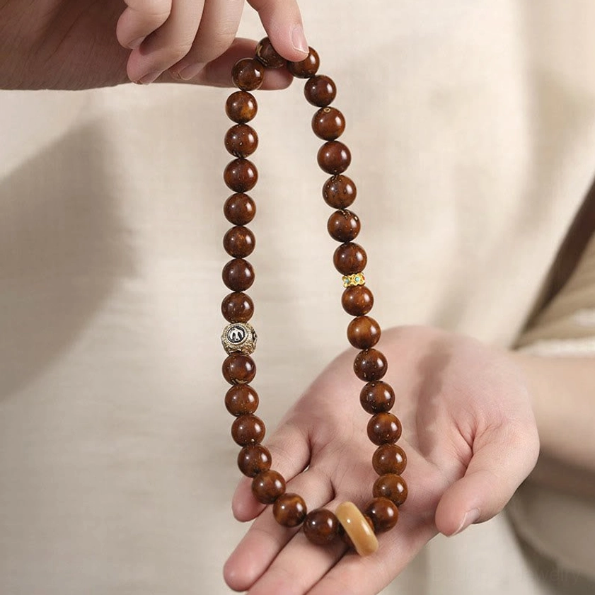 Hand-held bodhi seed prayer bracelet worn at eye level in indoor daily wear setting