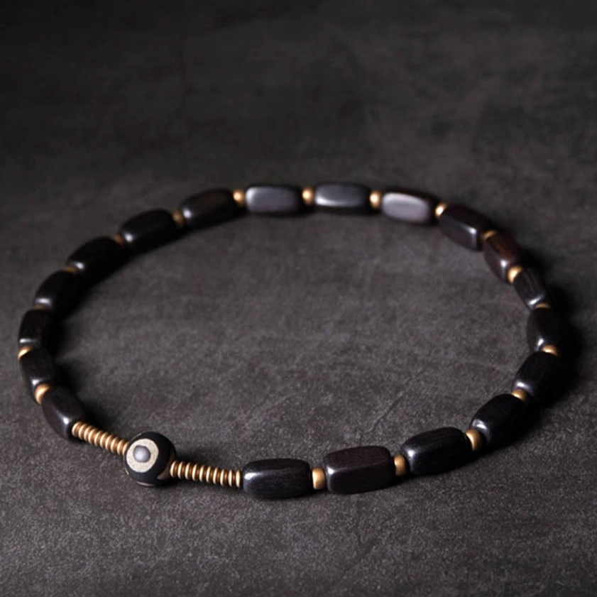 Double wrap ebony wood dzi bracelet with central nine-eye bead top-down view