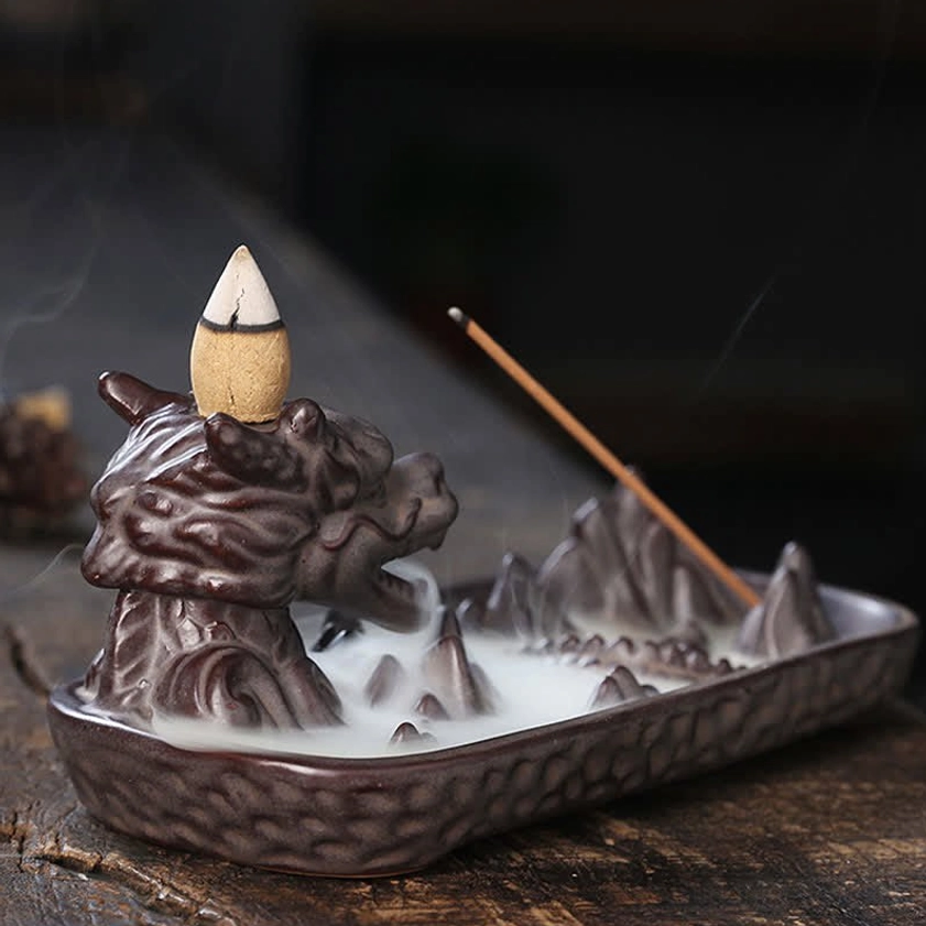 Dragon ceramic backflow incense burner in use with pointed cone and upright stick, showing mountain tray with backflow smoke waterfall
