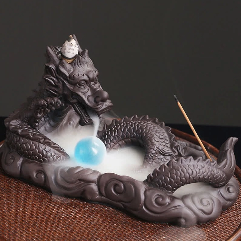 Dragon backflow incense burner overhead view with thick flowing incense smoke cascade, large blue glass orb and purple ceramic dragon sculpture
