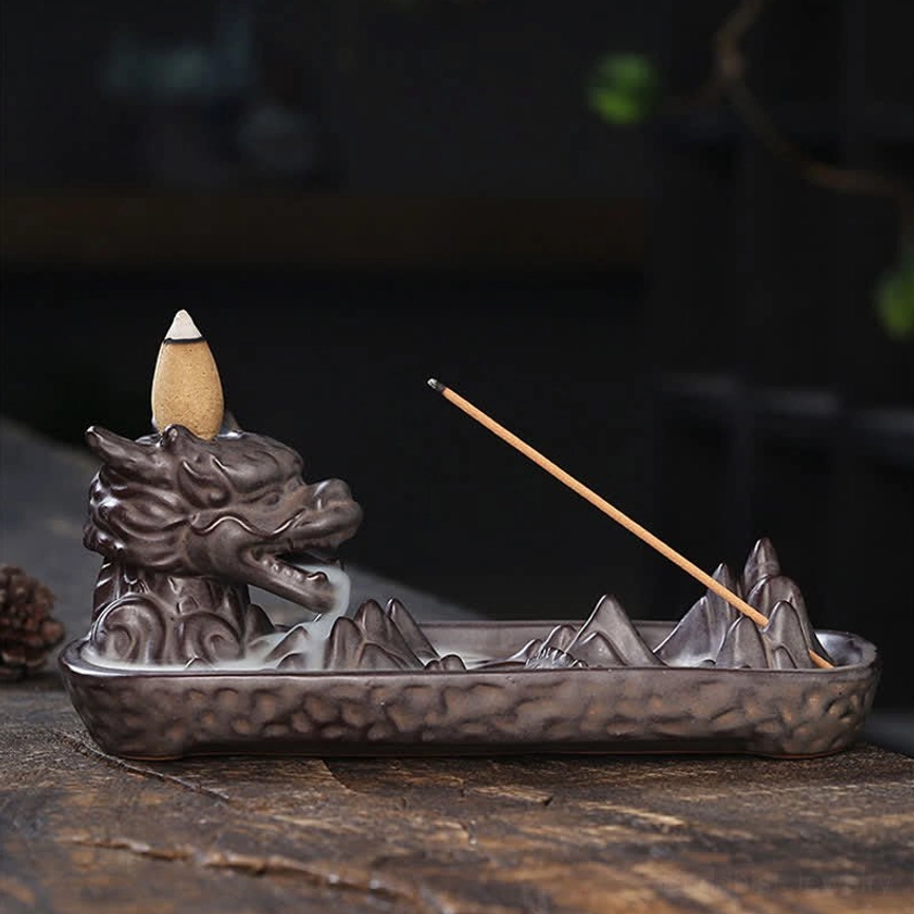 Left side profile of dragon ceramic backflow incense burner with incense cone on head and single stick, meditation room setting