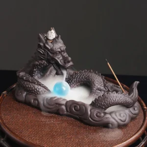 Dragon backflow incense burner with blue glass bead in front angled view, showcasing detailed dragon sculpture and downward-flowing incense smoke effect on woven bamboo coaster