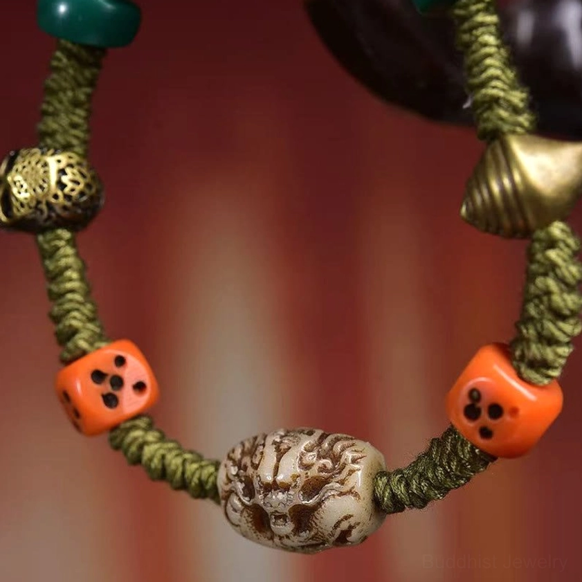 Macro close-up of dragon-carved central bead with orange dice beads and vintage metal skull charm