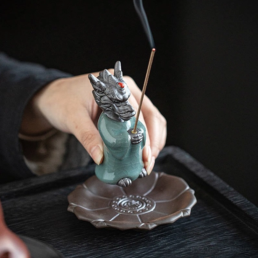 Hands assembling dragon incense burner on wooden tray, showing installation process with smoking incense