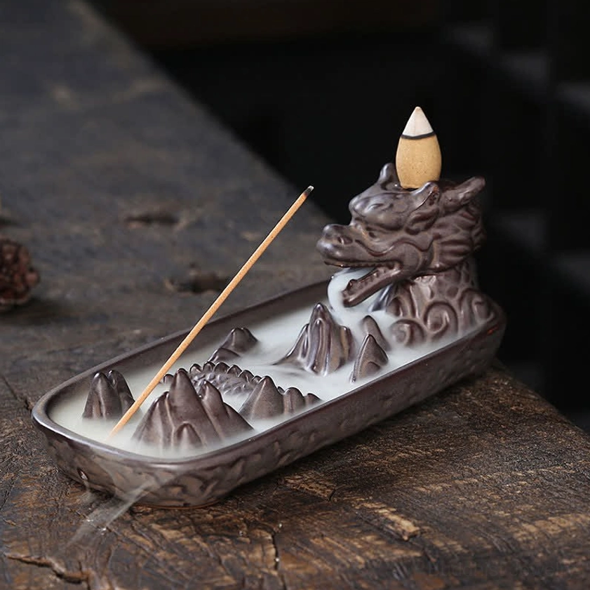 Handcrafted dragon ceramic incense burner with flowing backflow smoke cascade effect, right side angle view on rustic wooden table