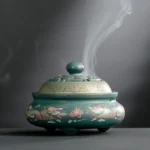 Teal green ceramic incense burner with dragon and floral patterns, hollow carved lid with spherical knob, backflow smoke fountain effect visible