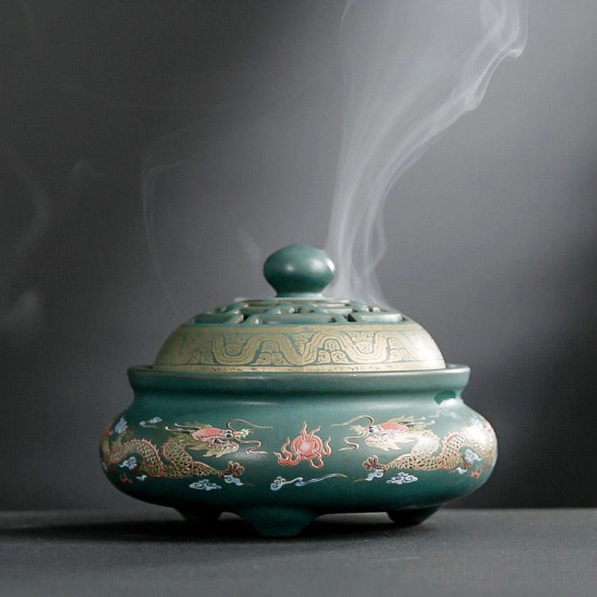 Teal green ceramic incense burner with dragon and floral patterns, hollow carved lid with spherical knob, backflow smoke fountain effect visible