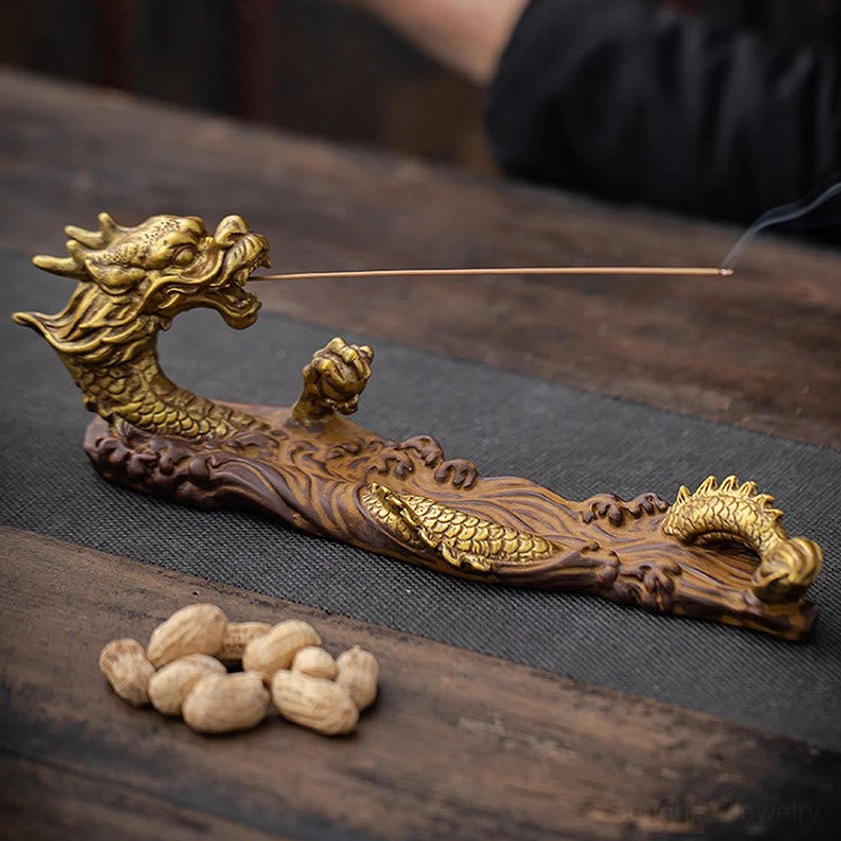 Dragon incense burner with lit incense stick burning and smoking, placed on wooden tea table with natural scene