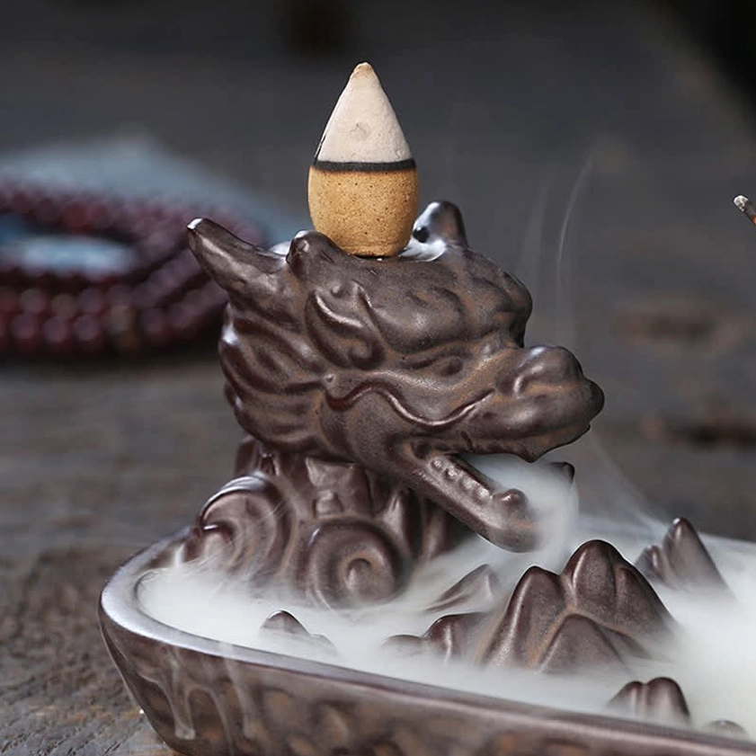 Close-up front view of intricate dragon head carving on ceramic incense burner with detailed texture and flowing backflow smoke