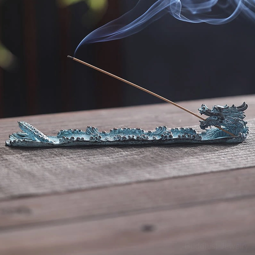 Full dragon body incense burner with burning incense and smoke, low perspective view on wooden table