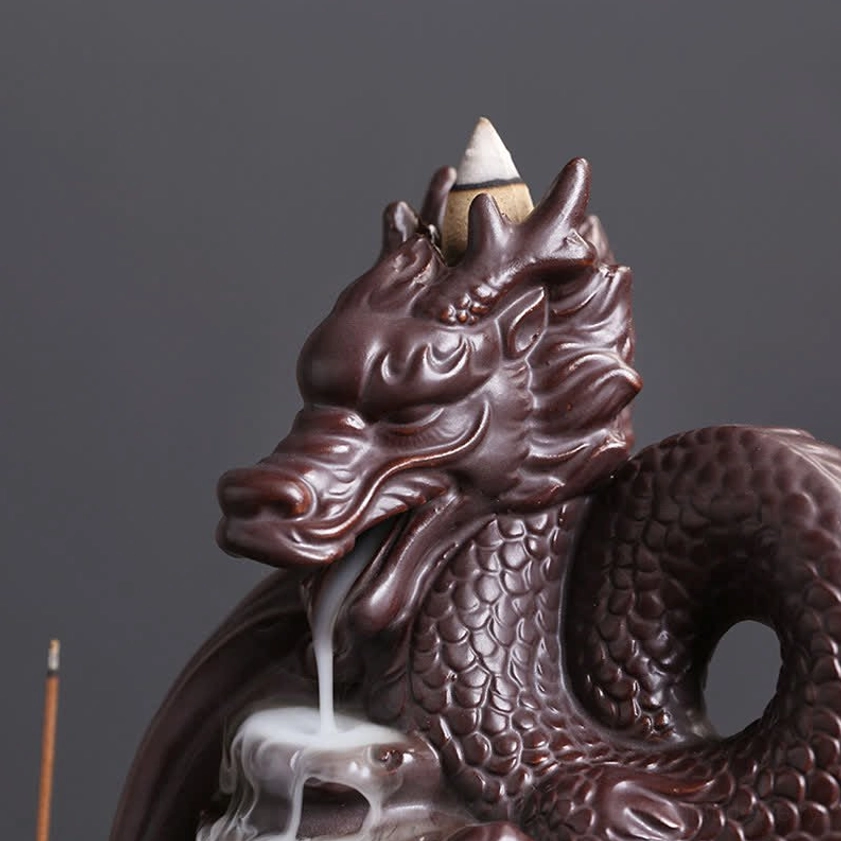 Close-up front view of dragon head on ceramic backflow incense burner with detailed carved facial features and smoke cascade